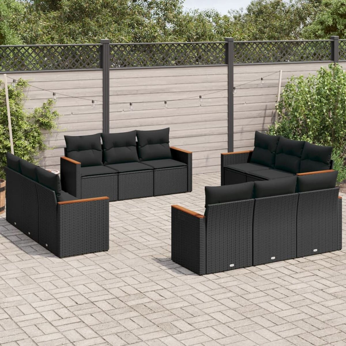 Schwarzes Outdoor-Sitzmöbelset aus Korbgeflecht mit schwarzen Kissen auf einer Ziegelterrasse.