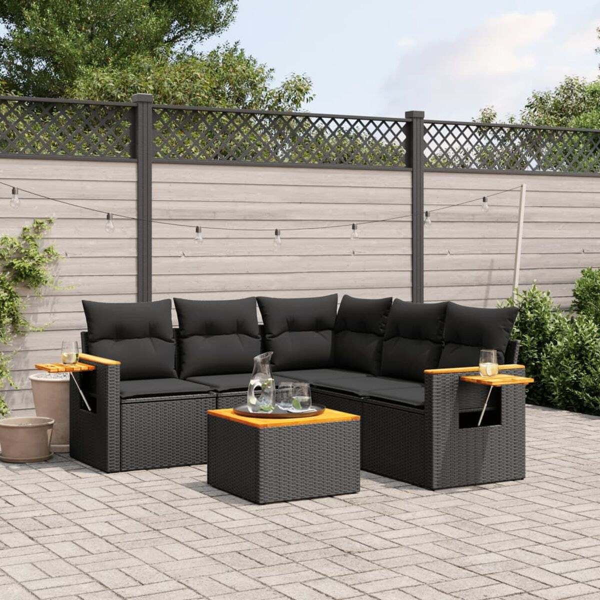 Schwarzes Ecksofa mit Beistelltischen, schwarzen Kissen und einem Couchtisch mit Holzplatte auf Terrasse.