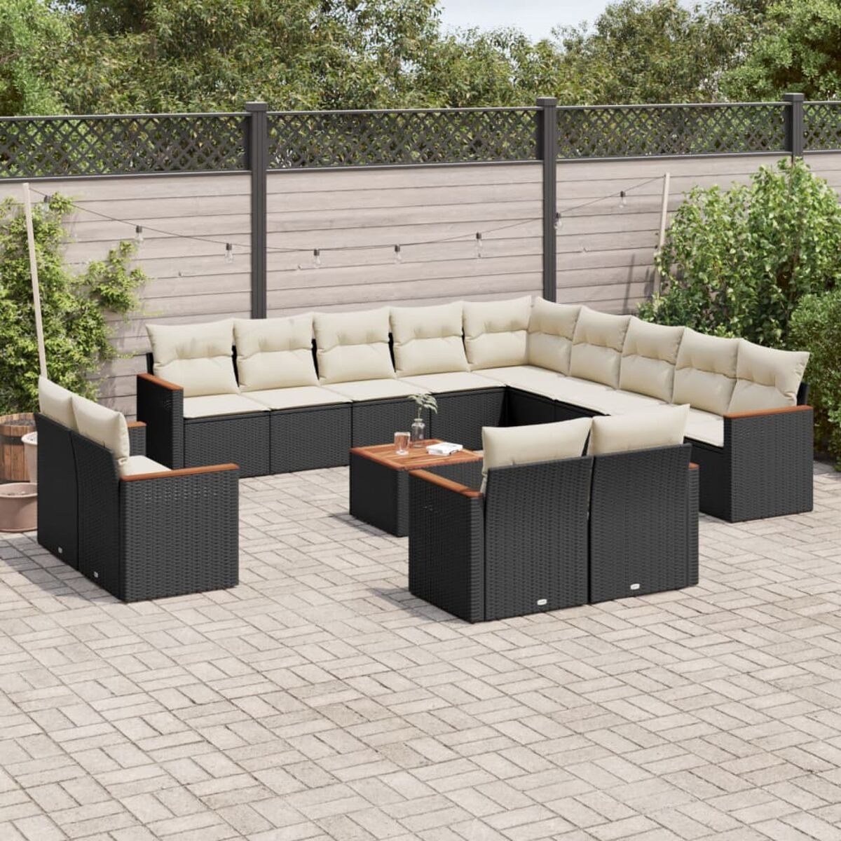 Terrassenmöbel-Set im Freien. Schwarzes Korbmöbel-Sofa und Stühle mit cremefarbenen Kissen.