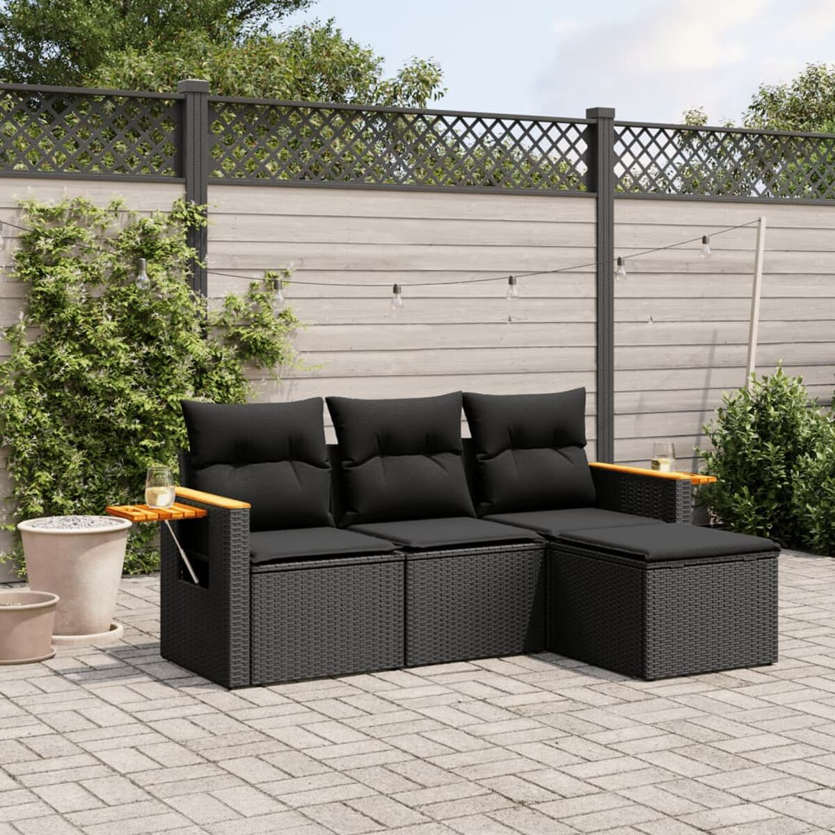 Schwarzes Outdoor-Sofa mit schwarzen Kissen und Holzarmlehnen, in einem Hinterhof.