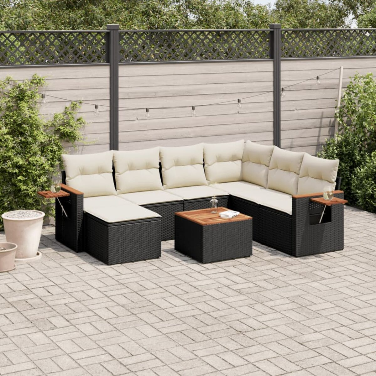 Schwarzes Outdoor-Möbelset aus Korbgeflecht mit beigen Kissen und einem Holztisch.