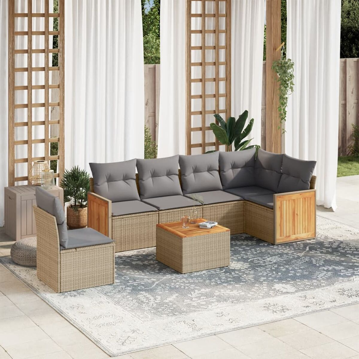 Beiges Rattansofaset mit grauen Kissen, Couchtisch und Stuhl auf einem Teppich auf einer Terrasse.
