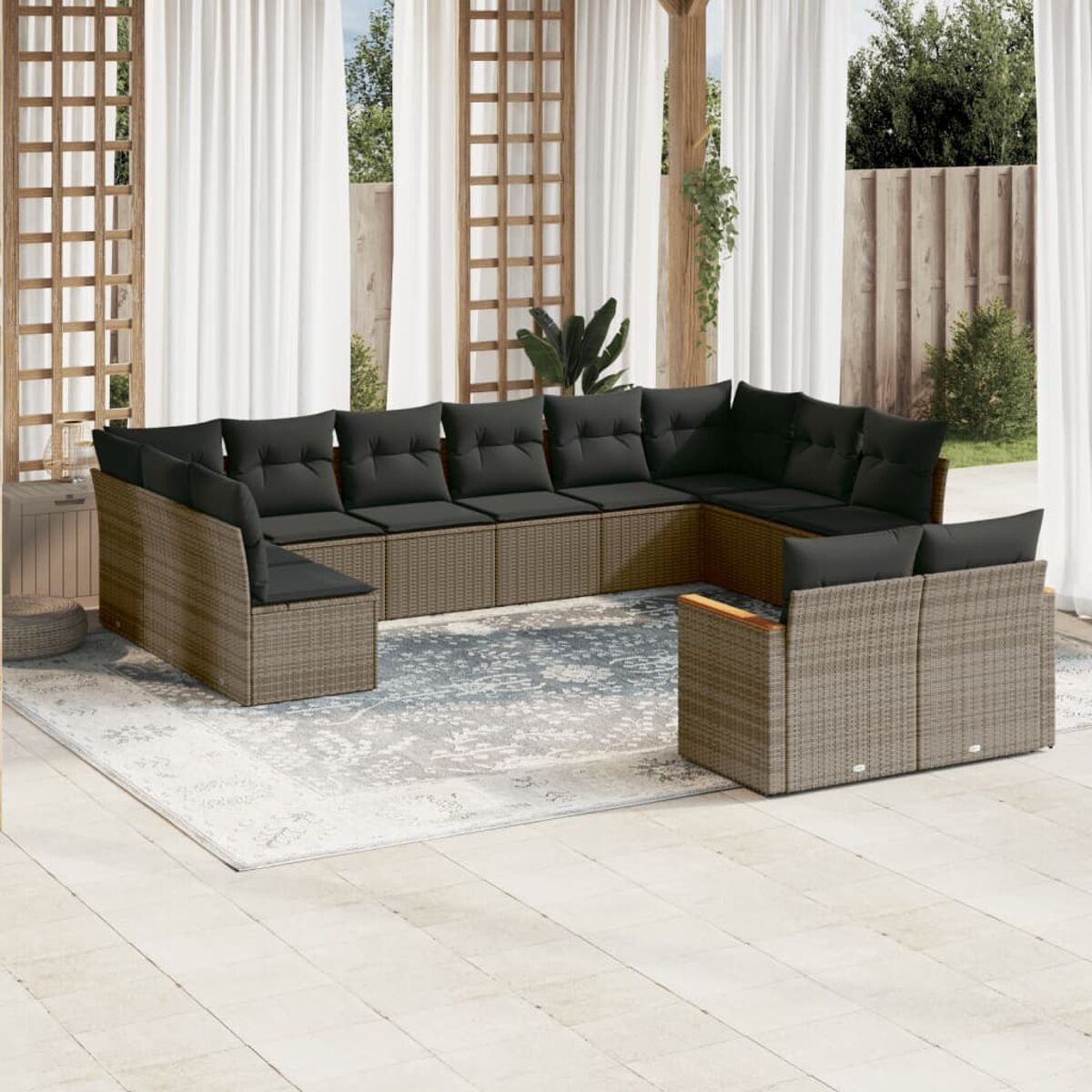 Rattan-Sofa-Set für den Außenbereich mit schwarzen Kissen. Der Hintergrund ist ein Teppich, ein Zaun und Vorhänge.