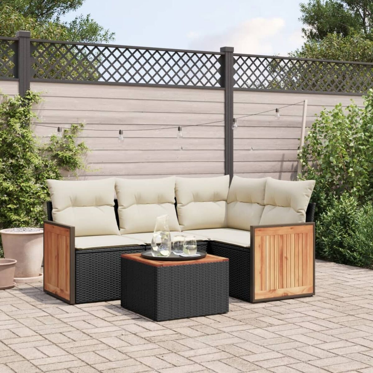 Rattan-Gartenmöbel auf einer Ziegelterrasse. Set hat Ecksofa, Tisch und Pflanzen.