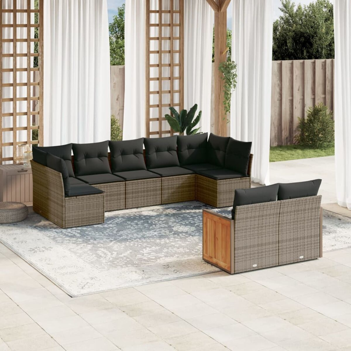 L-förmiges Outdoor-Sofa-Set aus Korbgeflecht mit schwarzen Kissen auf einem Teppich.