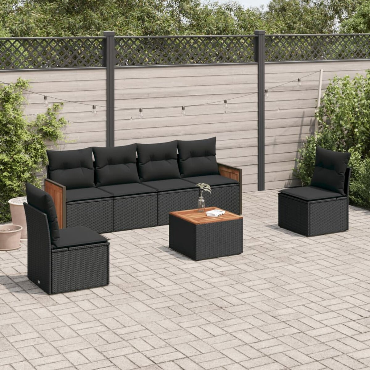 Terrasse im Freien mit schwarzen Korbmöbeln, darunter ein Sofa, Stühle und ein Couchtisch. Die Umgebung ist eine Terrasse.