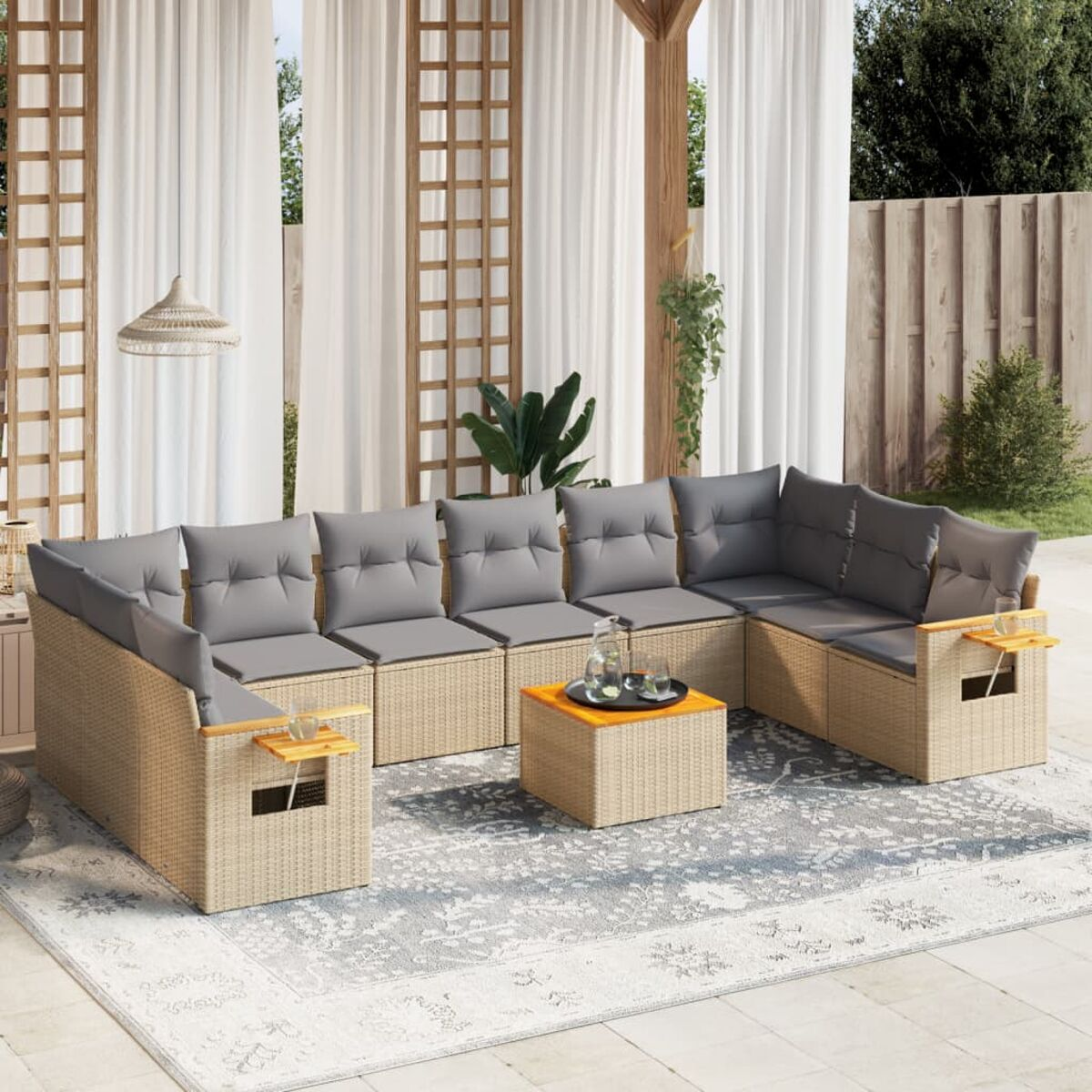 Rattan-Terrassenset mit Sofa, Ottomane und Couchtisch. Graue Kissen unter Pergola.