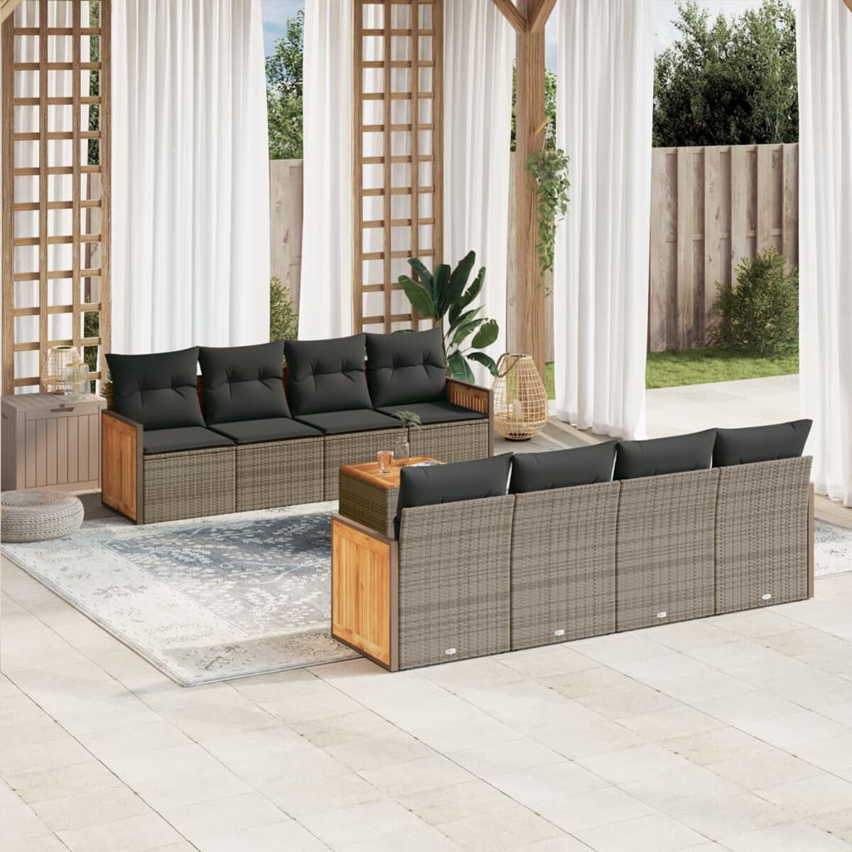 Terrassengarnitur mit Sofa, Tisch und Teppich. Weiße Vorhänge und Grün im Hintergrund.