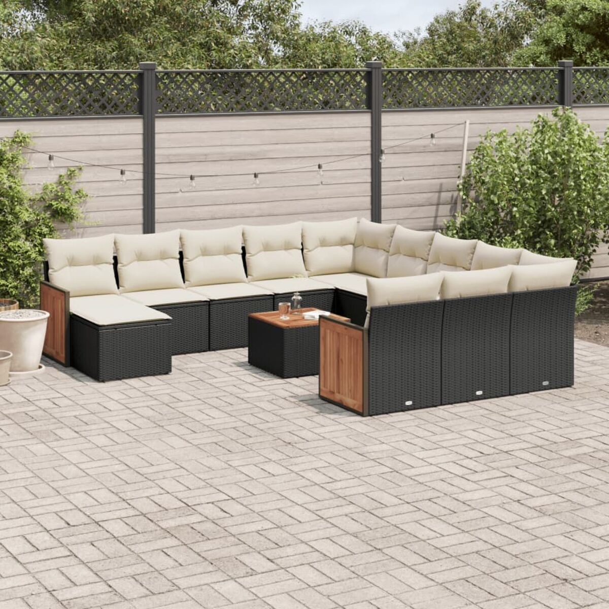Ein schwarzes Rattan-Ecksofa mit beigen Kissen und einem Holztisch auf einer Backstein-Terrasse.