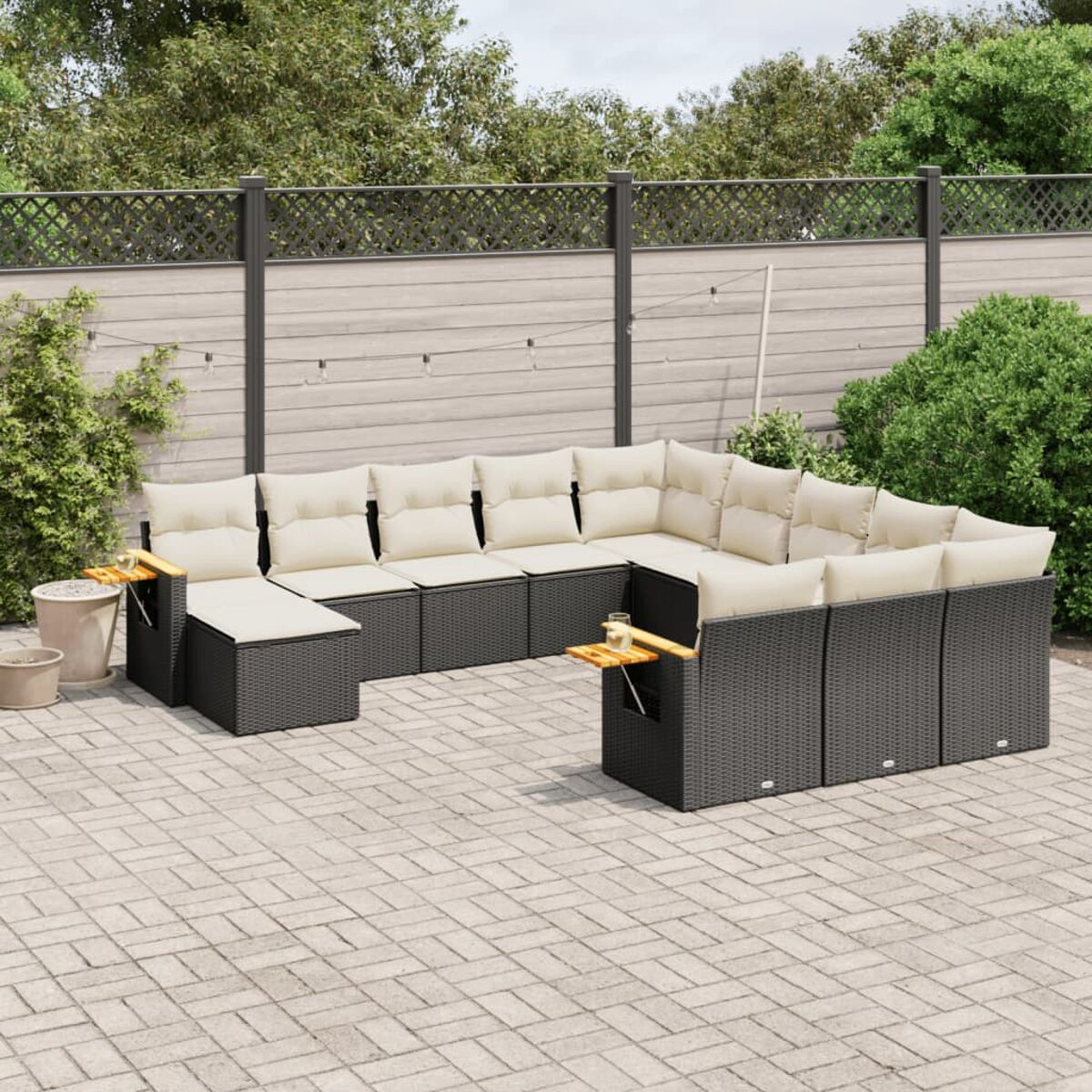 Rattan-Sofagarnitur mit beigefarbenen Kissen. Enthält ein Ecksofa und zwei Tische. Auf Ziegelterrasse.