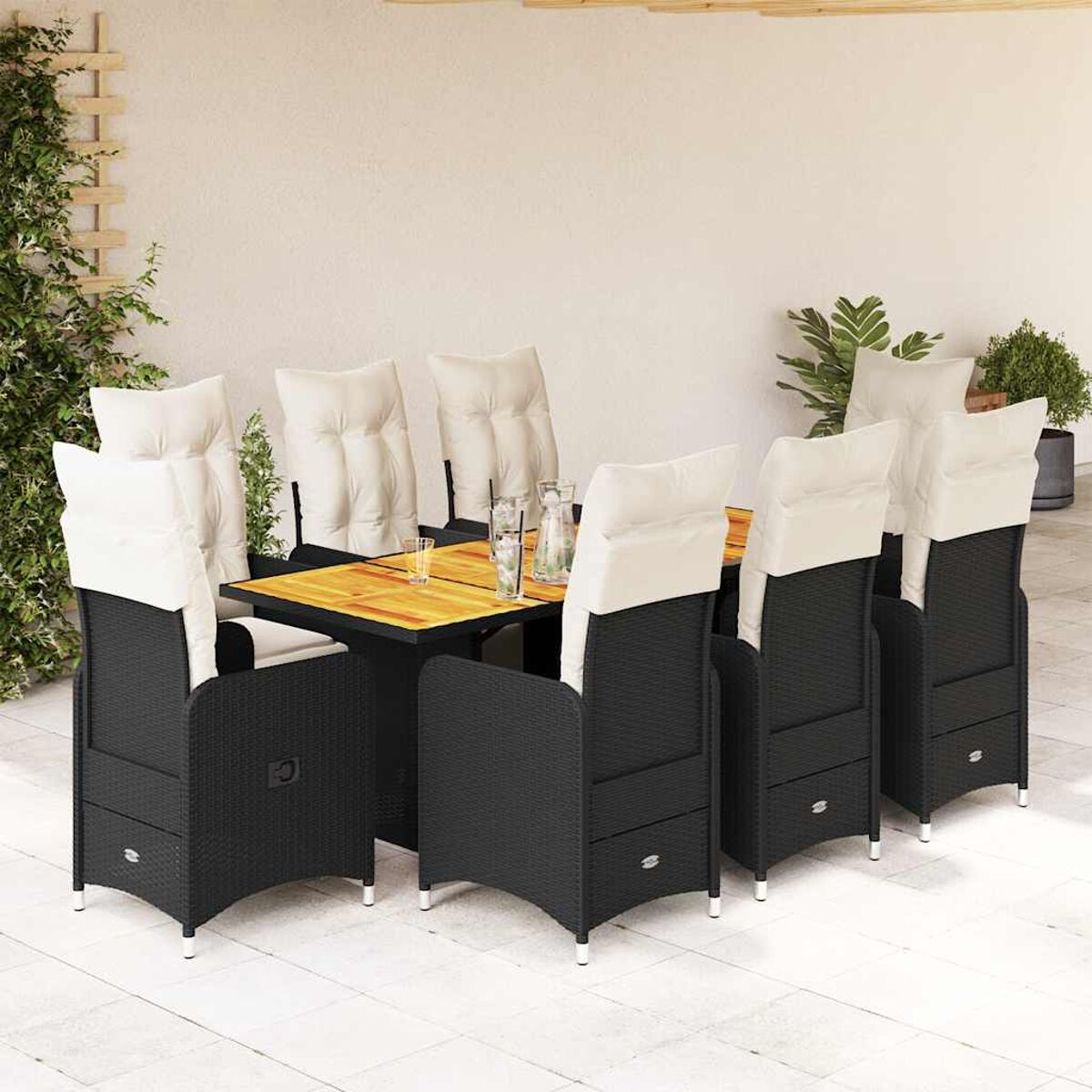 Set da pranzo da esterno in rattan nero con cuscini bianchi, su un patio. Tavolo e sedie presenti.
