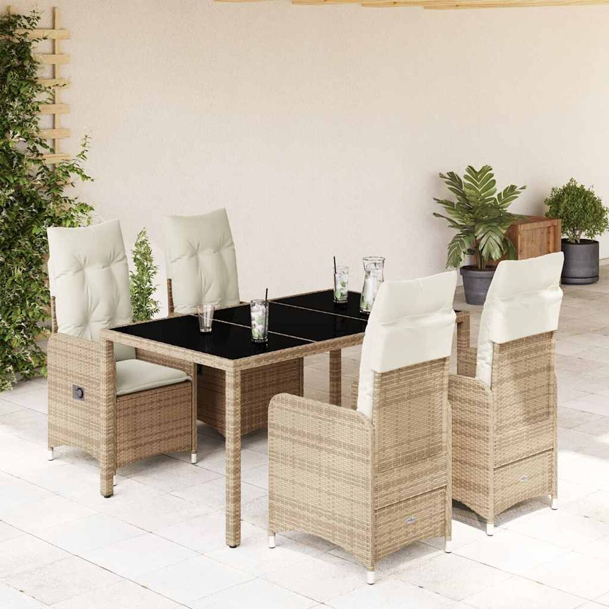 Set da pranzo in vimini per esterni. Include un tavolo in vetro nero, quattro sedie e piante.