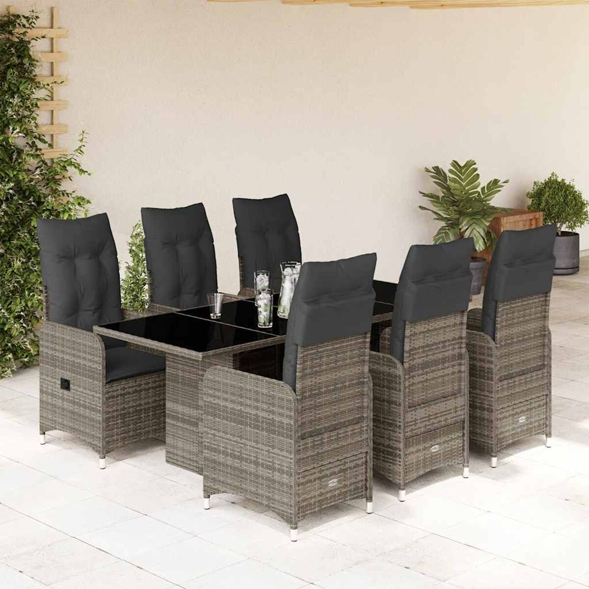 Set da pranzo per esterni con tavolo con piano in vetro e sedie. Vimini grigio. Cuscini neri.