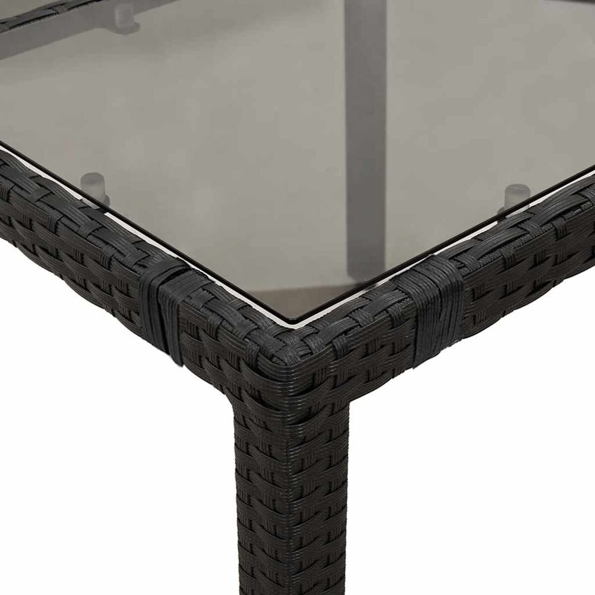 Primo piano di un angolo di tavolo nero intrecciato con piano in vetro. Anche la gamba del tavolo è nera.