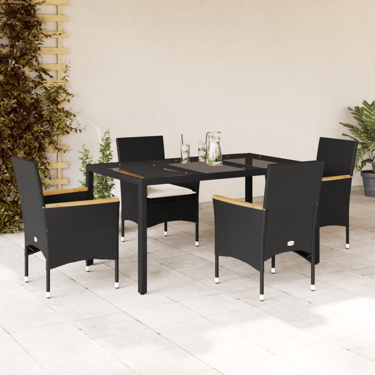Schwarzer Tisch und Stühle auf der Terrasse. Getränke auf dem Tisch. Grüne Pflanzen im Hintergrund.