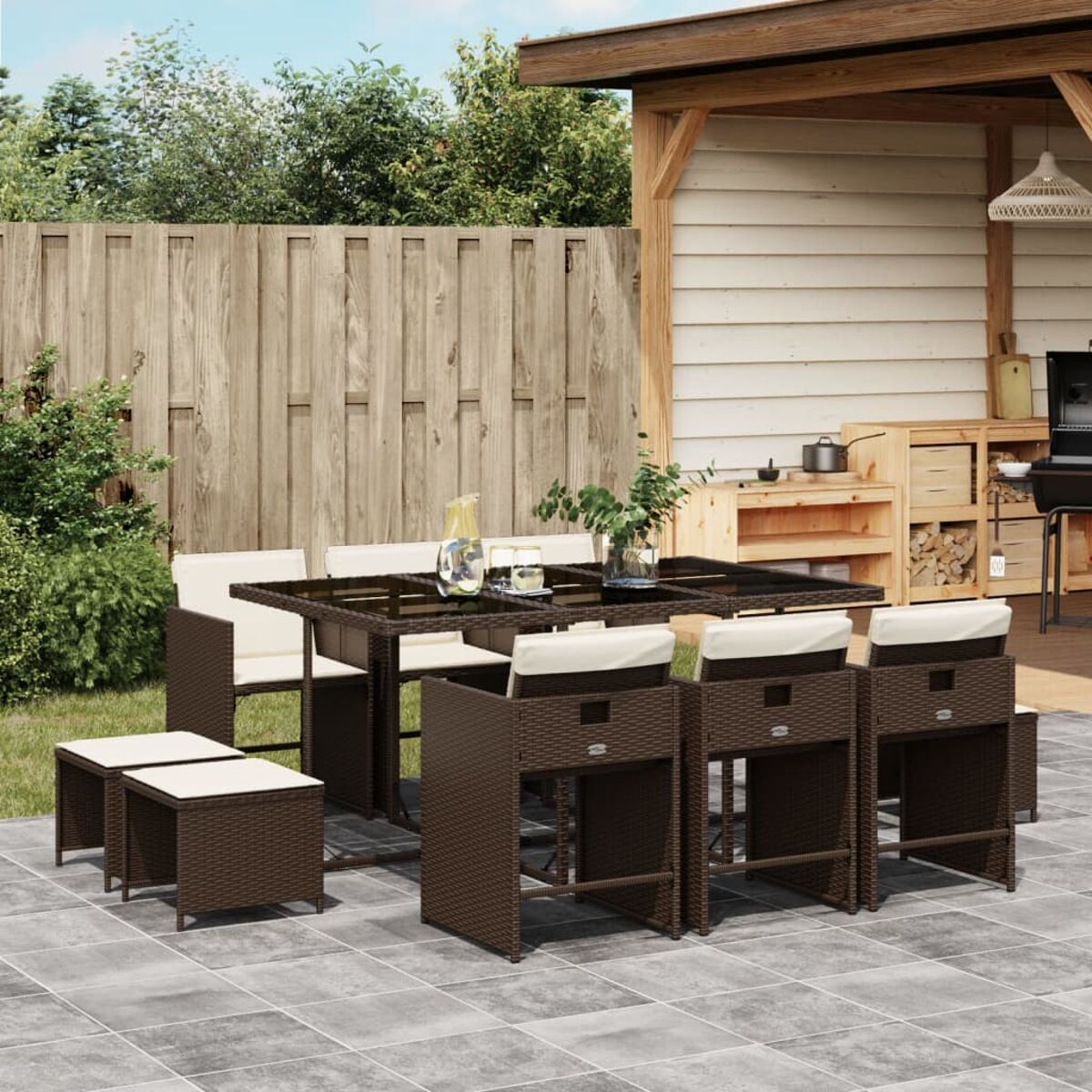 Braunes Outdoor-Set aus Korbgeflecht mit Tisch, Hockern und Stühlen mit cremefarbenen Kissen. Gartenumgebung.