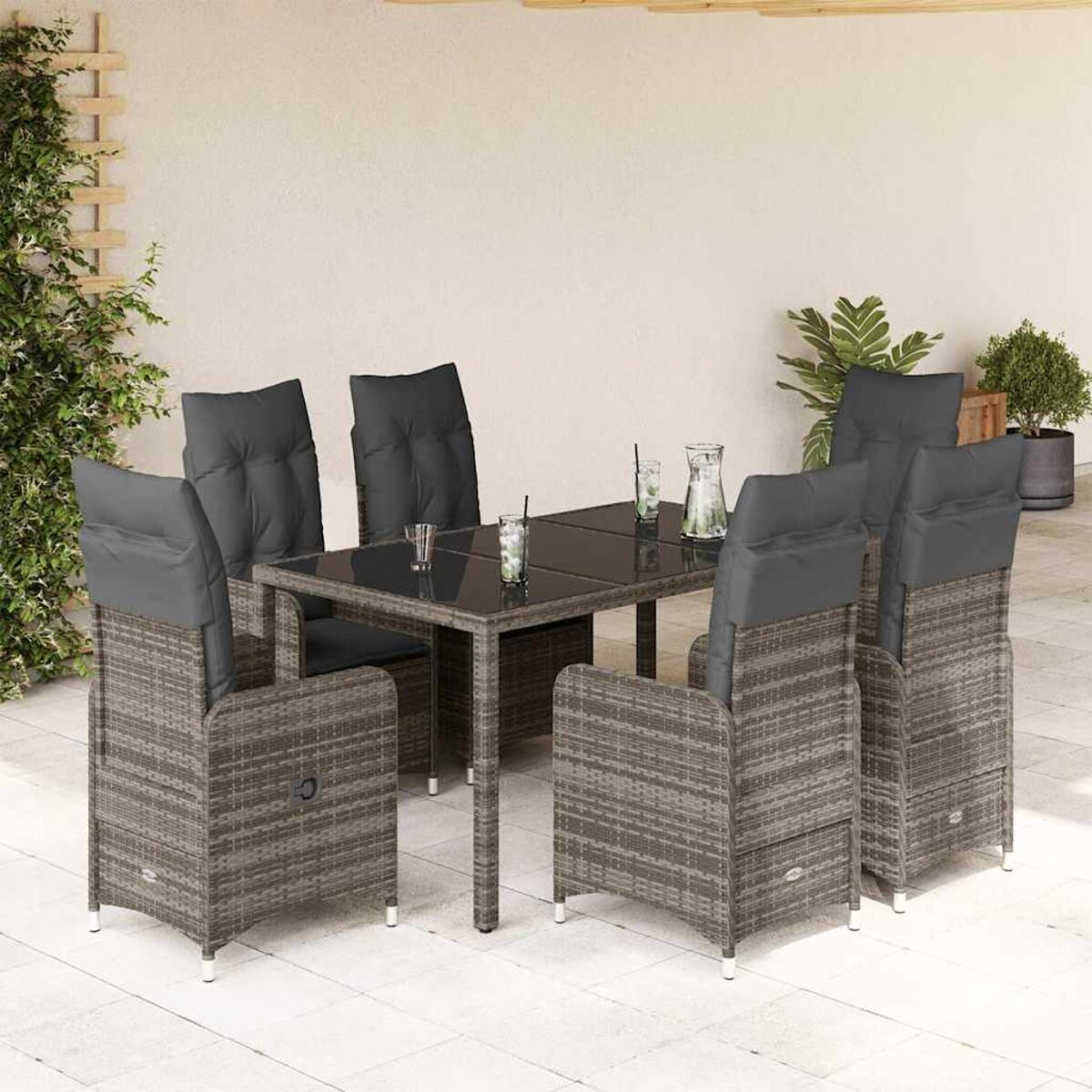 Set da pranzo in vimini da esterno con cuscini grigi. Il tavolo ha un piano in vetro. Su un patio.