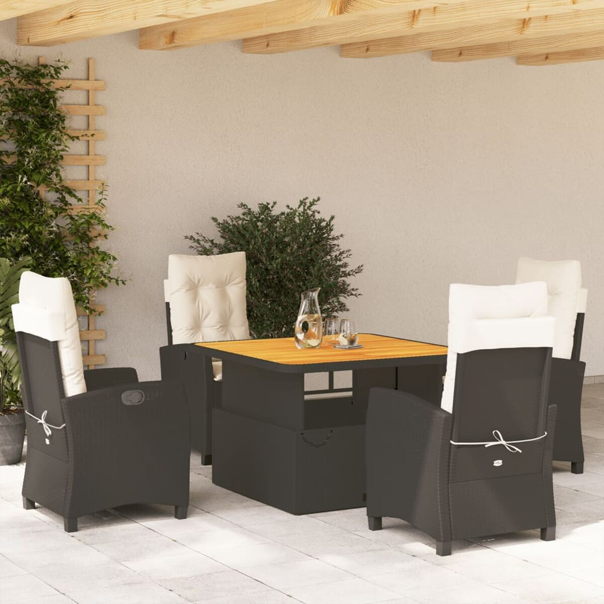 Outdoor-Sitzgruppe mit Tisch, Stühlen und Kissen. Hintergrund: Wand mit Pflanzen.