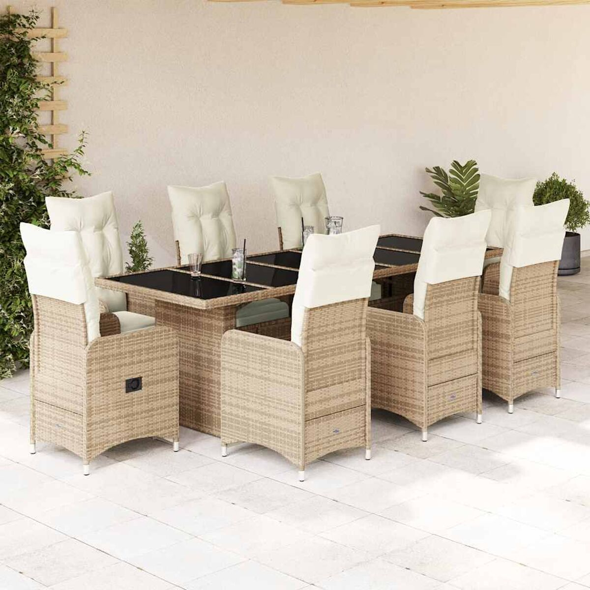 Un set da pranzo da patio con tavolo e sedie, circondato da piante e un muro bianco.