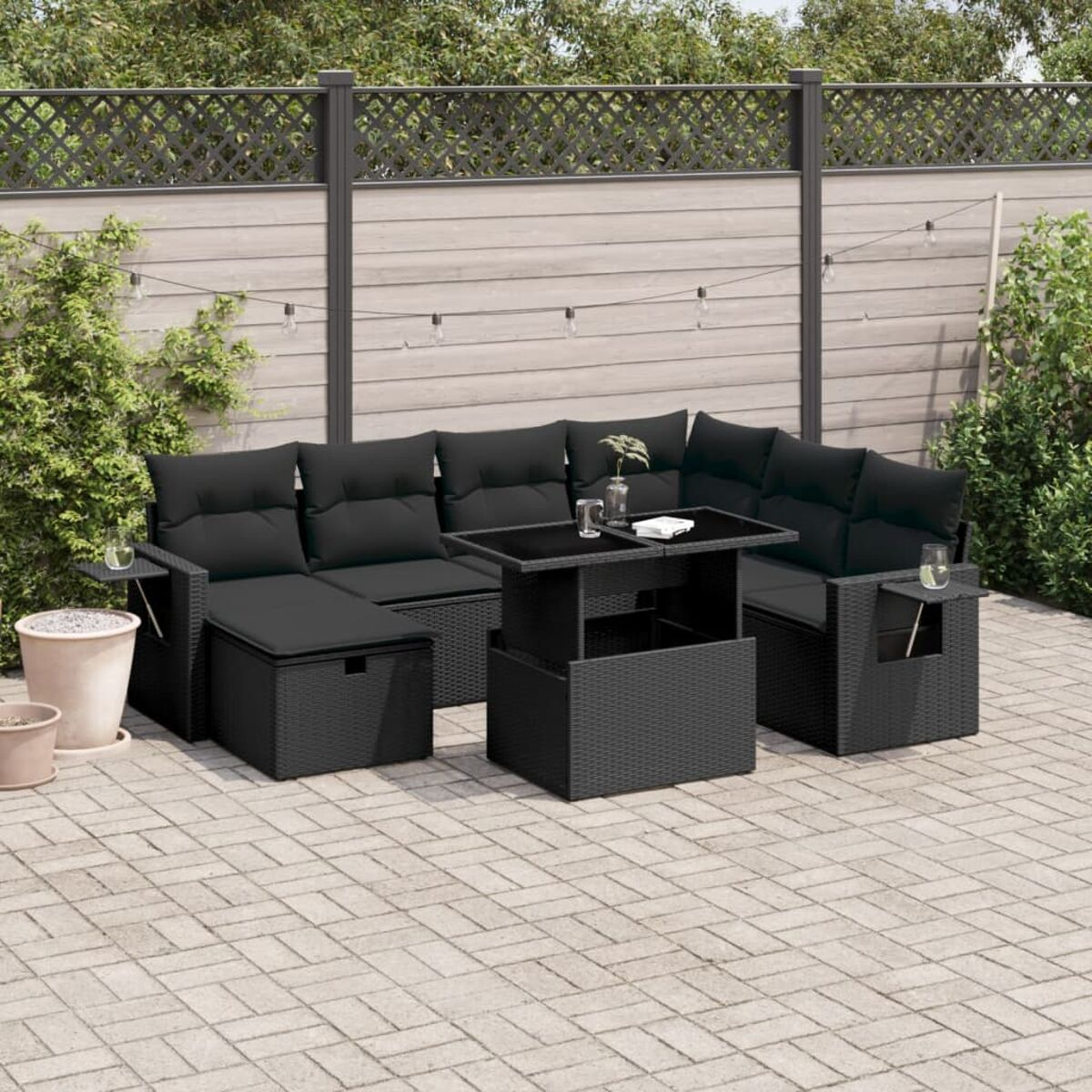 Schwarzes Outdoor-Ecksofa mit Couchtisch. Auf einer Terrasse mit Holzzaun.