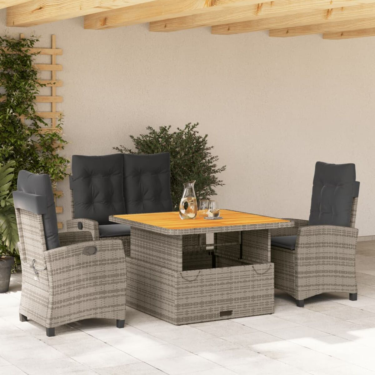 Tavolo in rattan con due sedie e un divano. Ambientazione esterna con bicchieri e tavolo in legno.