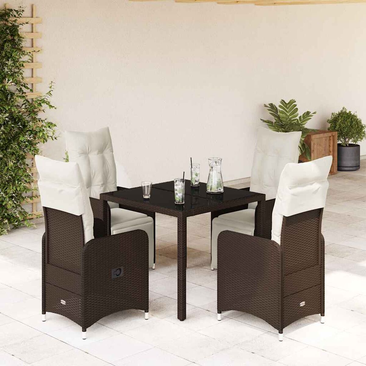 Set da pranzo all'aperto con tavolo in vetro e sedie in rattan marrone scuro, con cuscini bianchi. Su un patio.