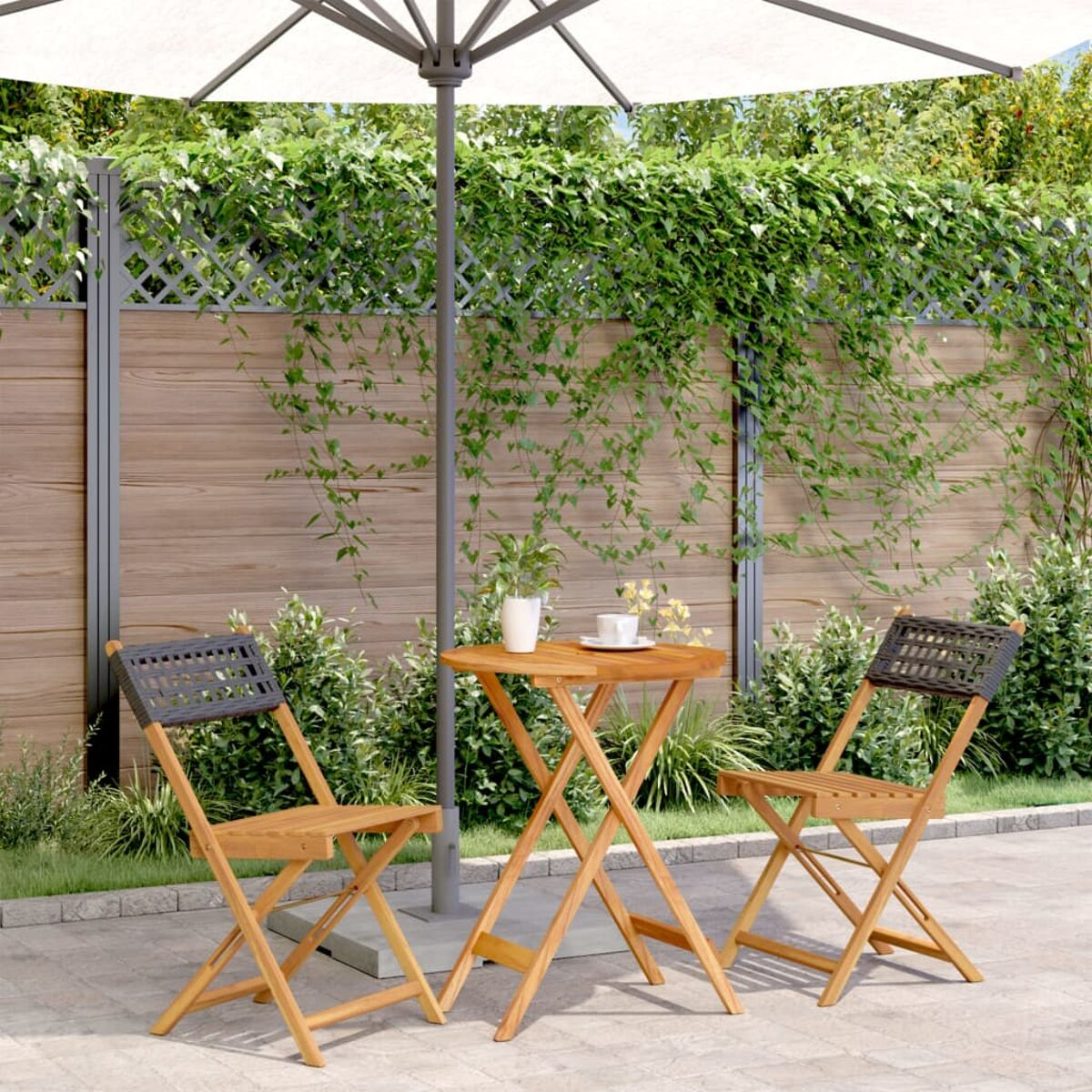 Zwei Holzstühle mit kleinem Tisch und Sonnenschirm im Garten. Grünes Laub.