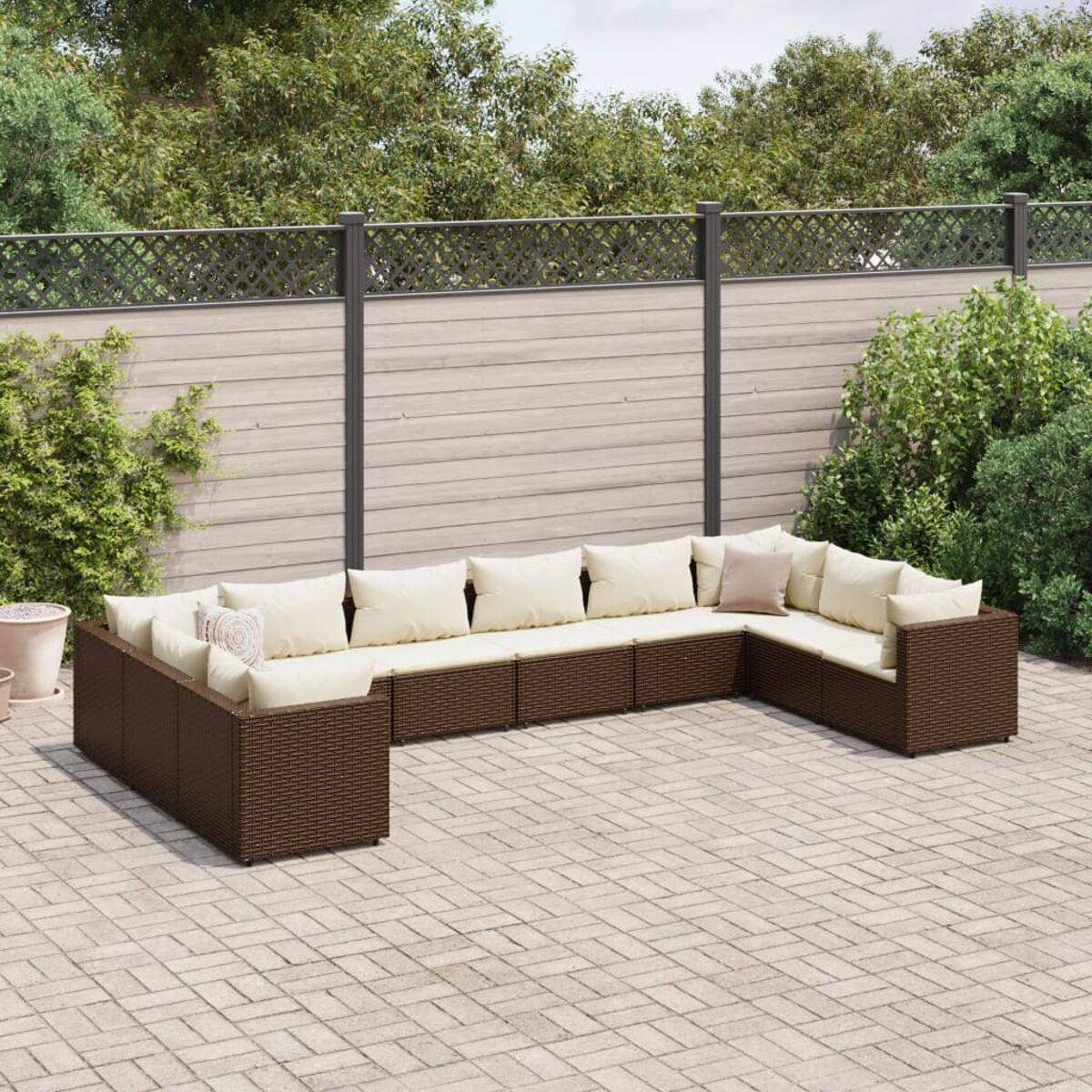Un sofá seccional de exterior marrón con cojines blancos en un patio.