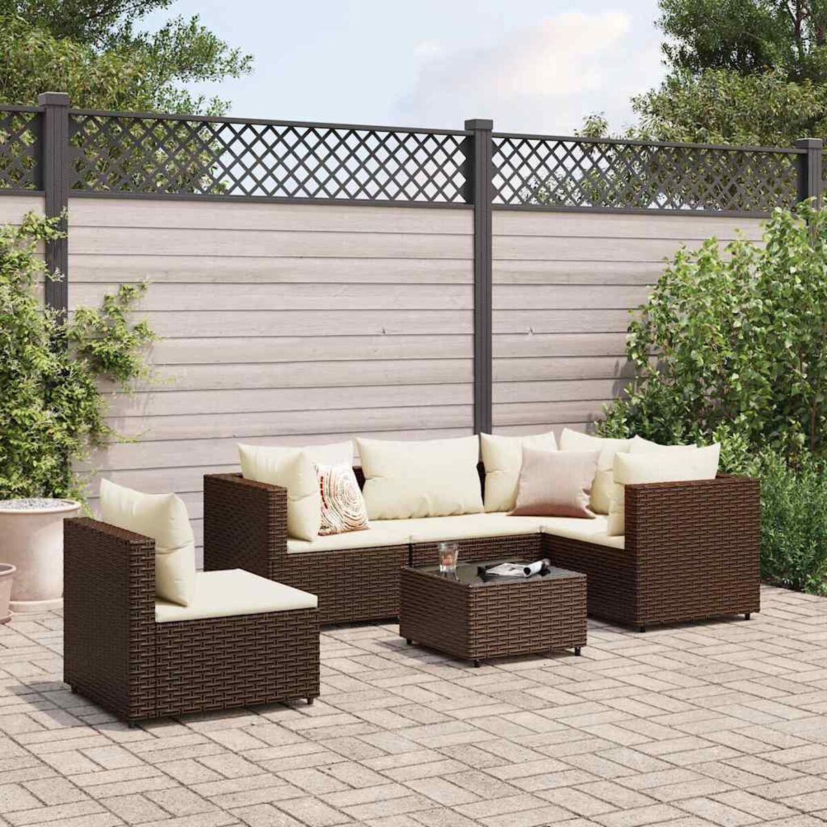 Juego de patio: muebles de mimbre marrón, mesa y cojines en patio.