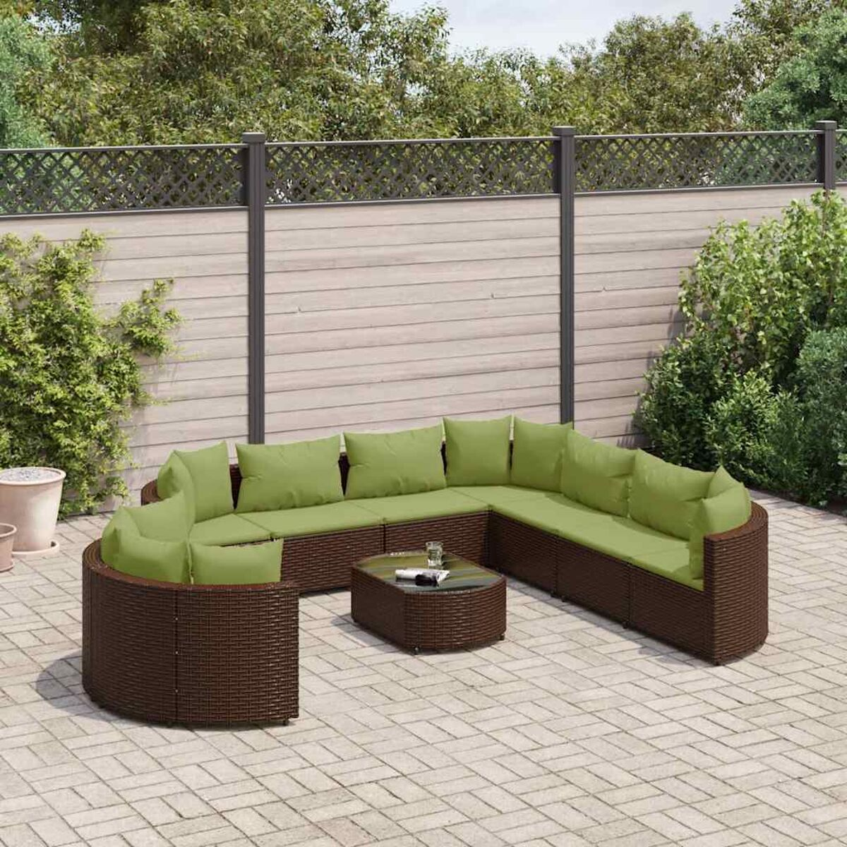 Gebogenes braunes Outdoor-Sofa mit grünen Kissen und einem kleinen Tisch. Ziegel-Patio-Setting.
