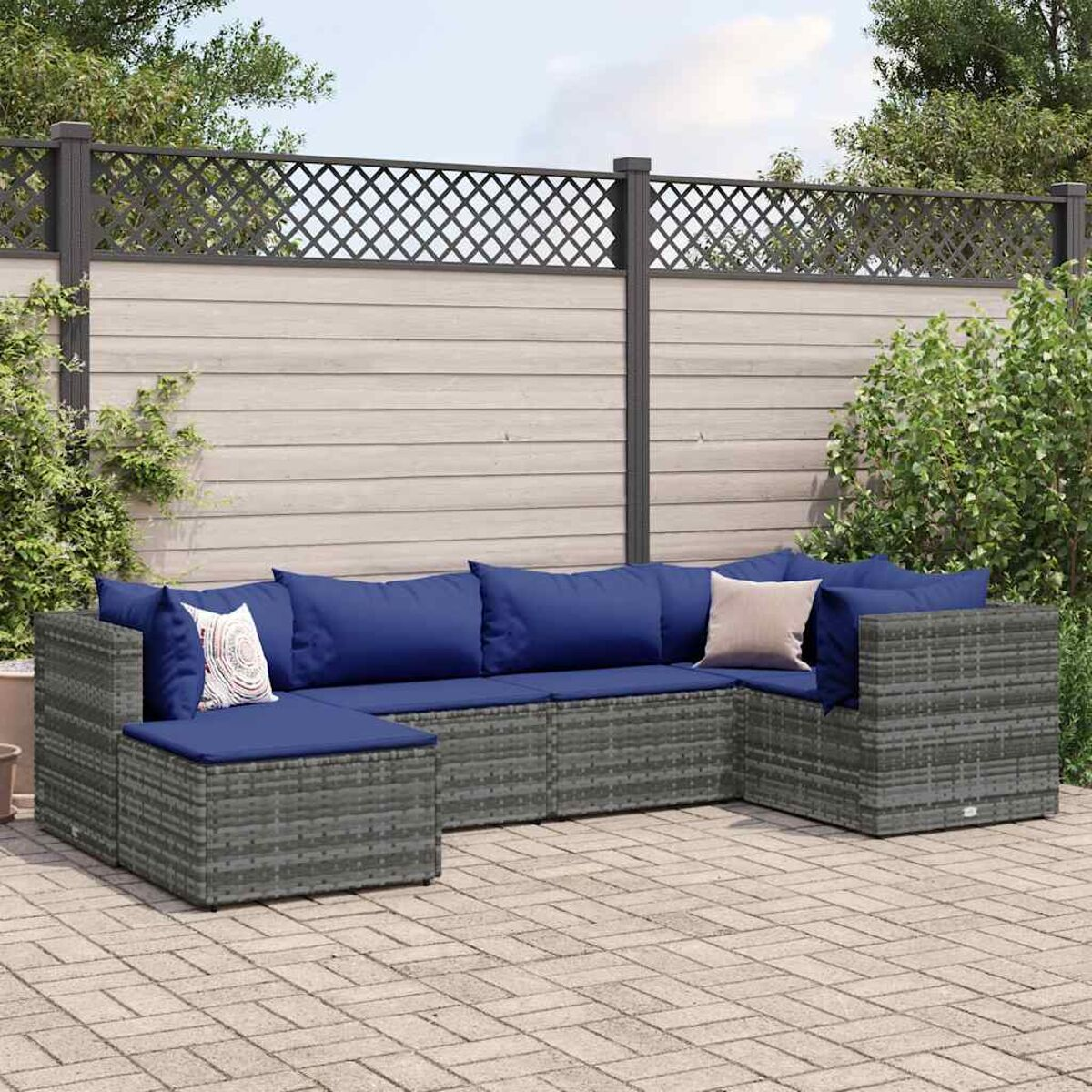 Divano componibile da esterno con cuscini e cuscini blu su un patio pavimentato. Sfondo recintato.
