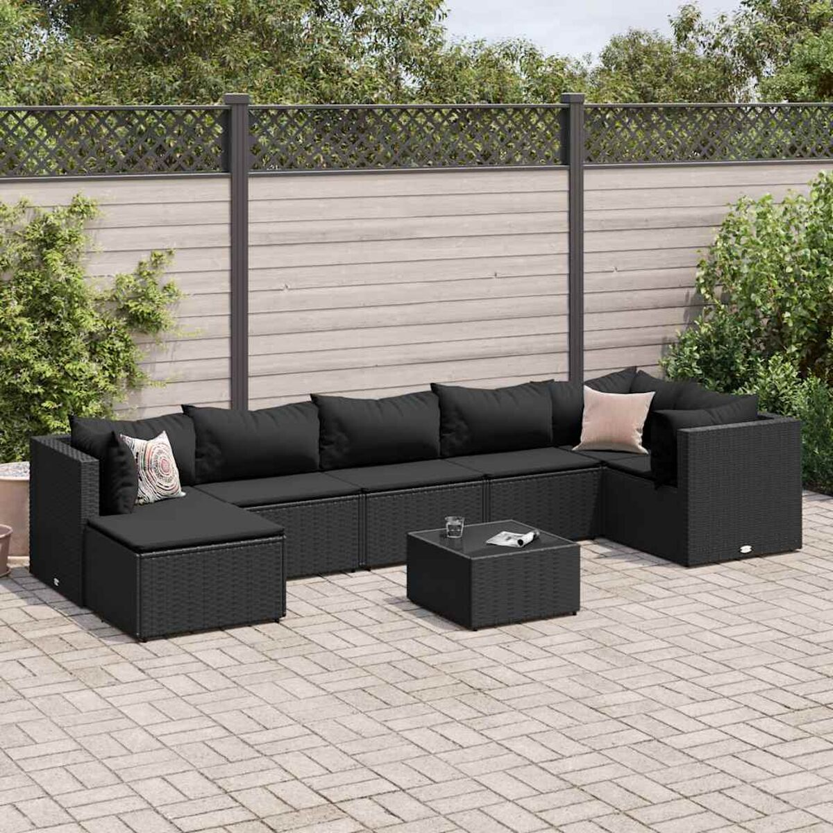 Un set di divani componibili da esterno in vimini nero con un tavolino quadrato su un patio.