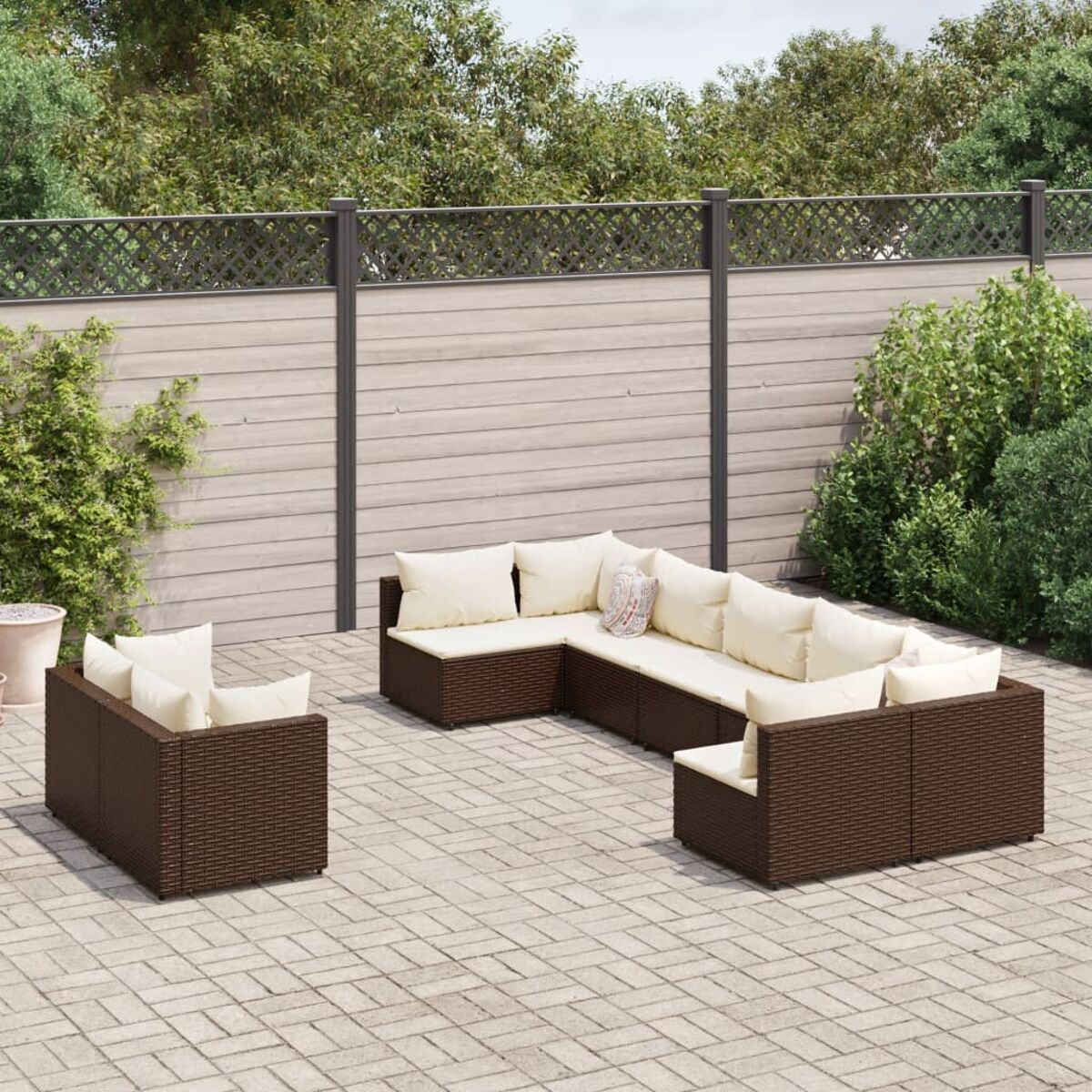 Outdoor-Ecksofa-Set aus braunem Korbgeflecht auf einer Terrasse mit Pflanzen.