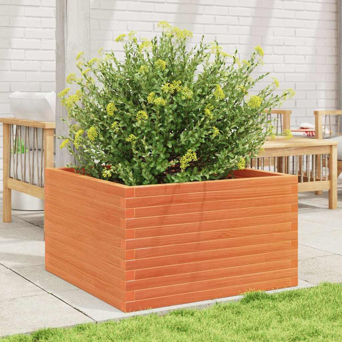 Holzpflanzer mit orangefarbenem Farbton, gefüllt mit grünen Pflanzen und gelben Blüten. Auf einer Terrasse.