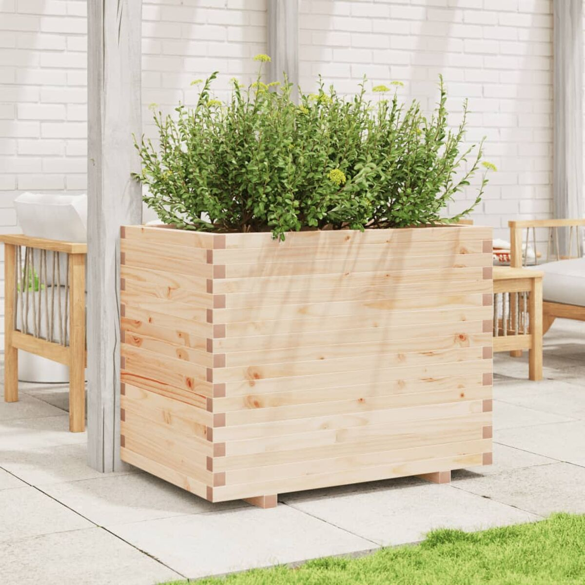 Großer Holzpflanzkübel mit grünem Laub. Der Pflanzkübel steht auf einer Ziegelterrasse.
