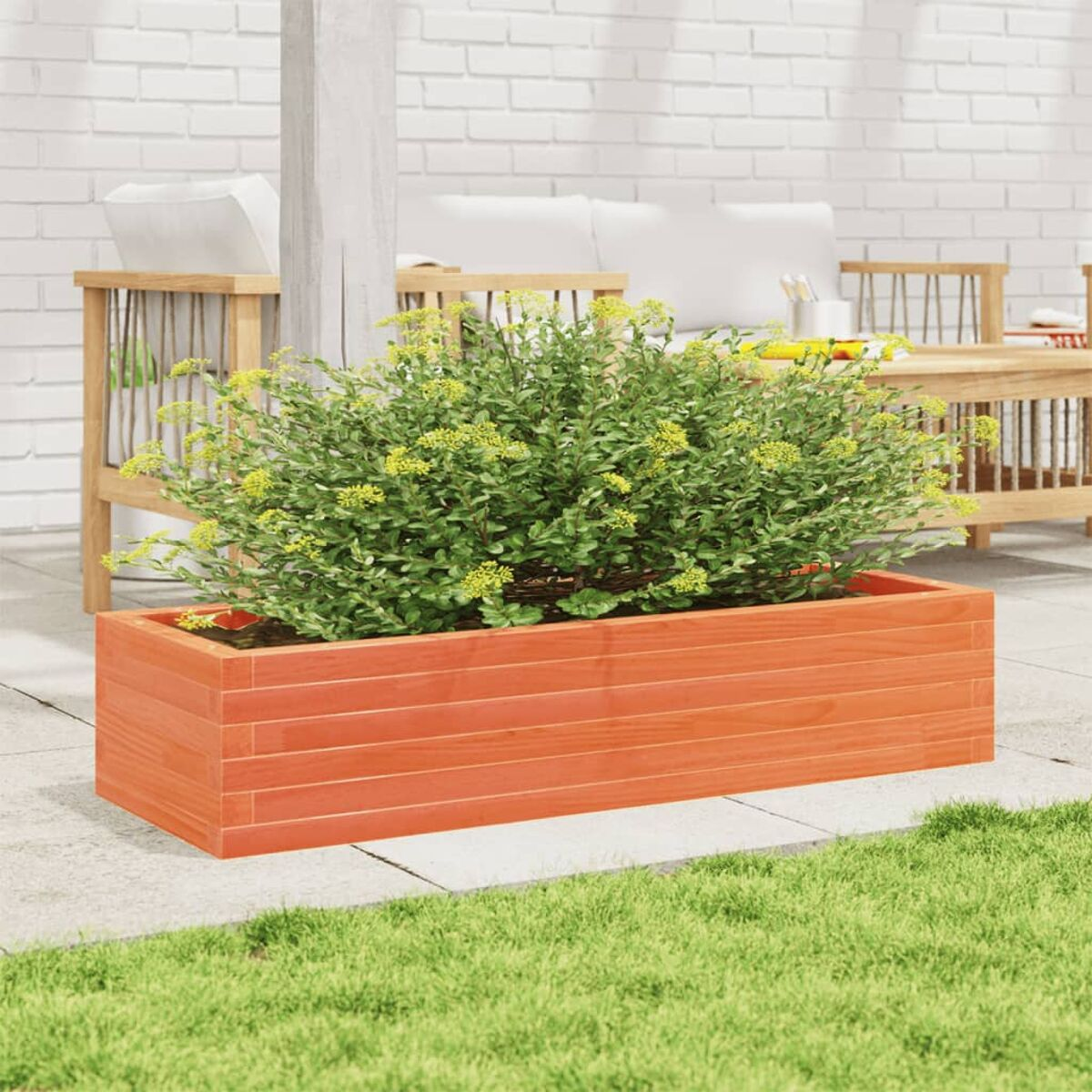 Oranger Holzblumenkasten mit grünen Pflanzen auf einer Terrasse mit grünem Gras.