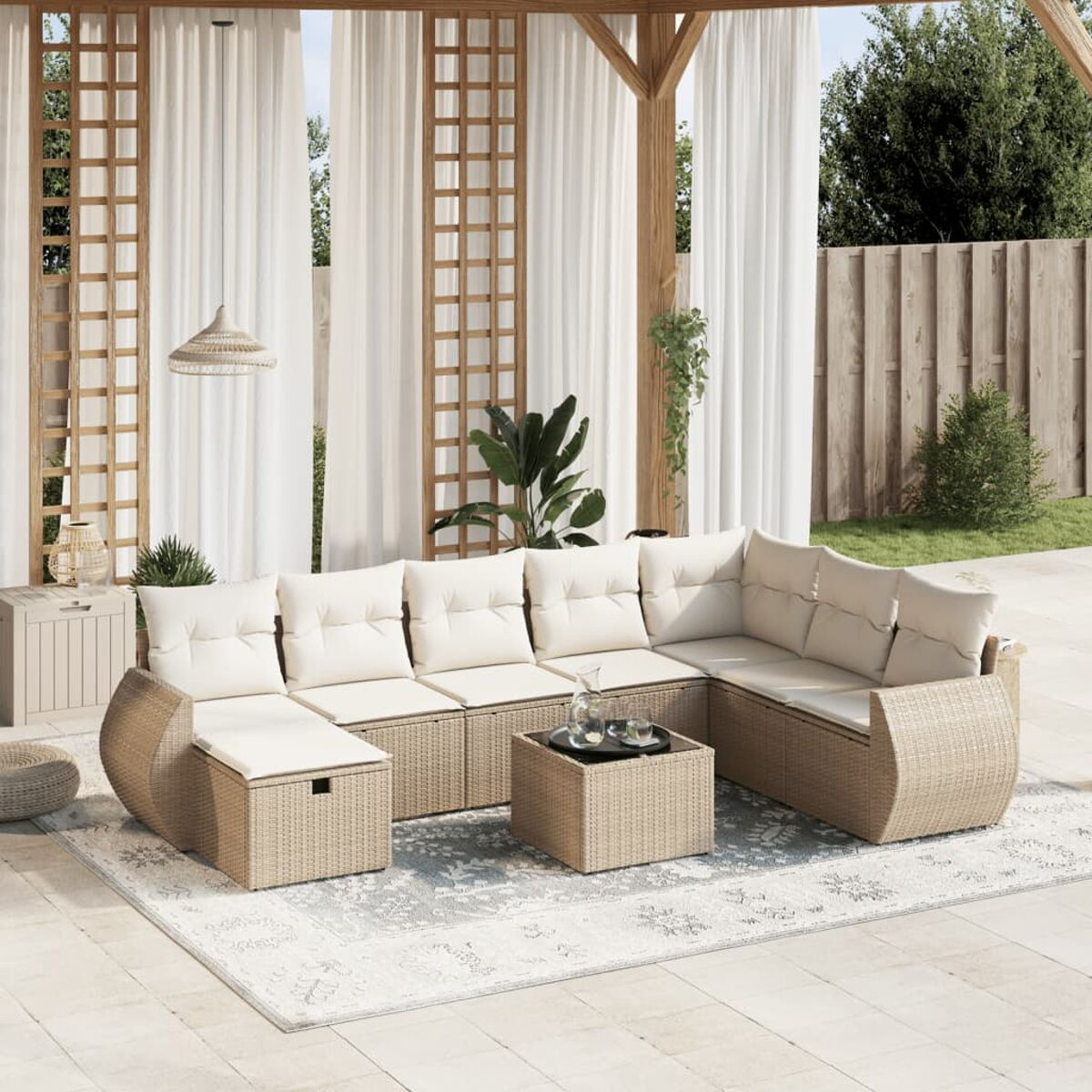 Rattansofa-Set im Freien mit Kissen, einem Couchtisch und einem Teppich auf einer Terrasse mit Vorhängen.