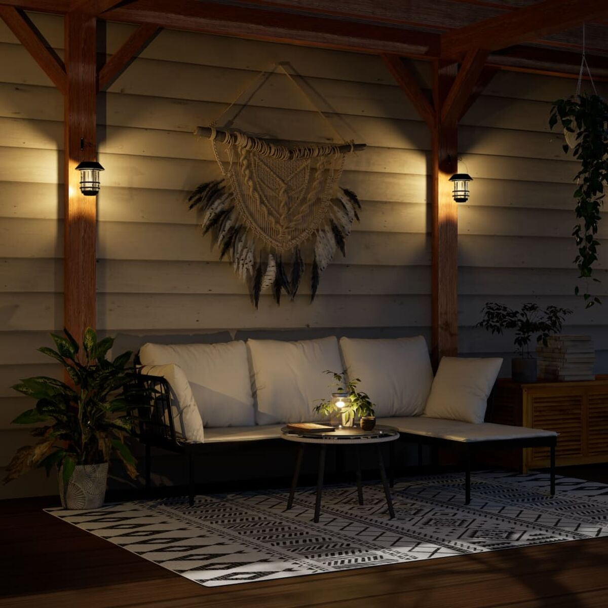 Sitzbereich im Freien bei Nacht. Sofa und kleiner Tisch mit Lampe, dekoriert mit einem Traumfänger.