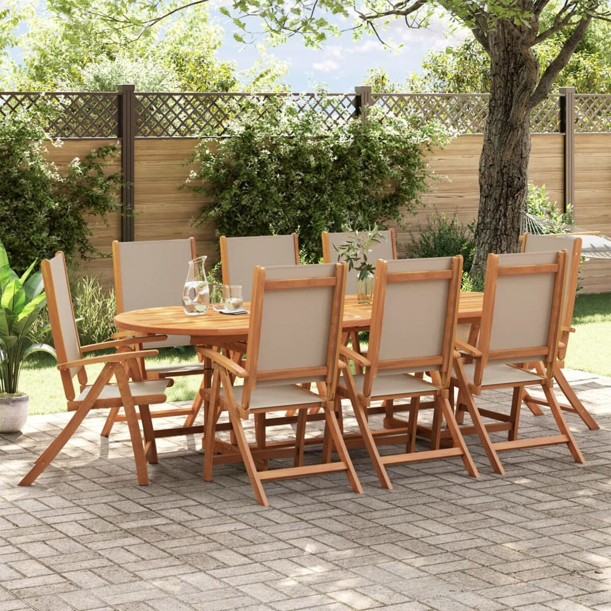 Set da pranzo all'aperto con tavolo e sedie in legno su un patio, con sfondo di giardino.