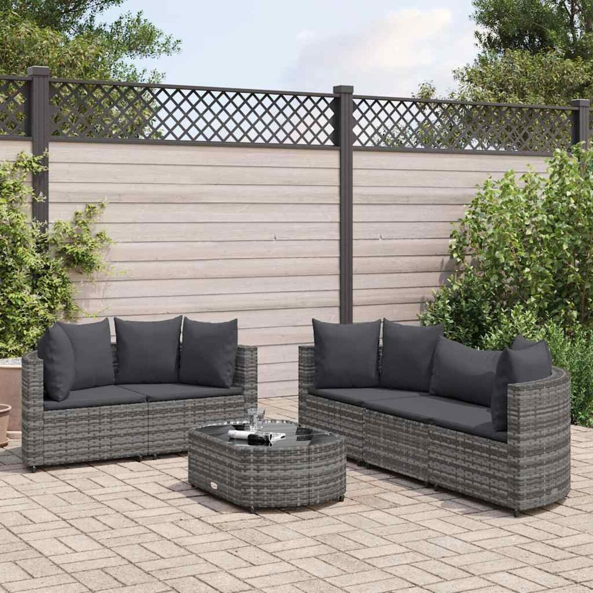 Graues Rattan-Sofaset. Graue Kissen. Couchtisch. Hintergrund der Ziegelterrasse.