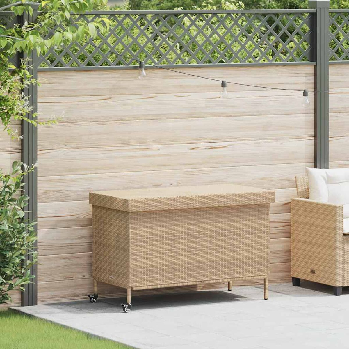 Ein Rattan-Stauraum mit Rädern steht auf einer Terrasse mit einem Holzzaun im Hintergrund.