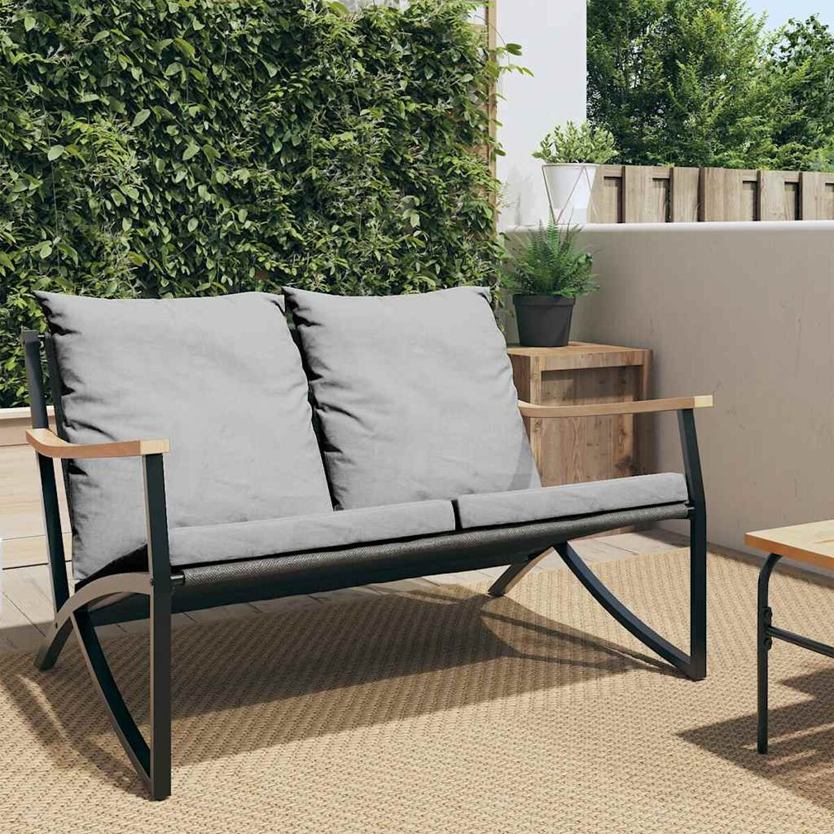 Outdoor-Ecksofa mit zwei grauen Kissen, schwarzem Rahmen und Holzarmlehnen.