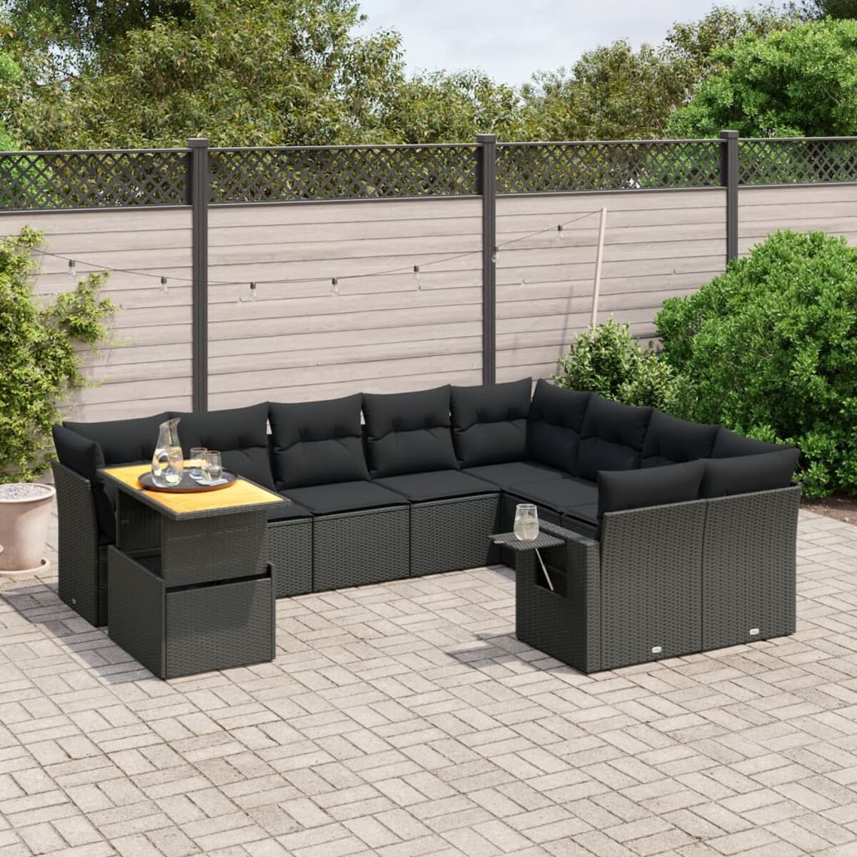 Outdoor-Sofa-Garnitur aus schwarzem Korbgeflecht mit Kissen und Tisch auf Backstein-Terrasse.