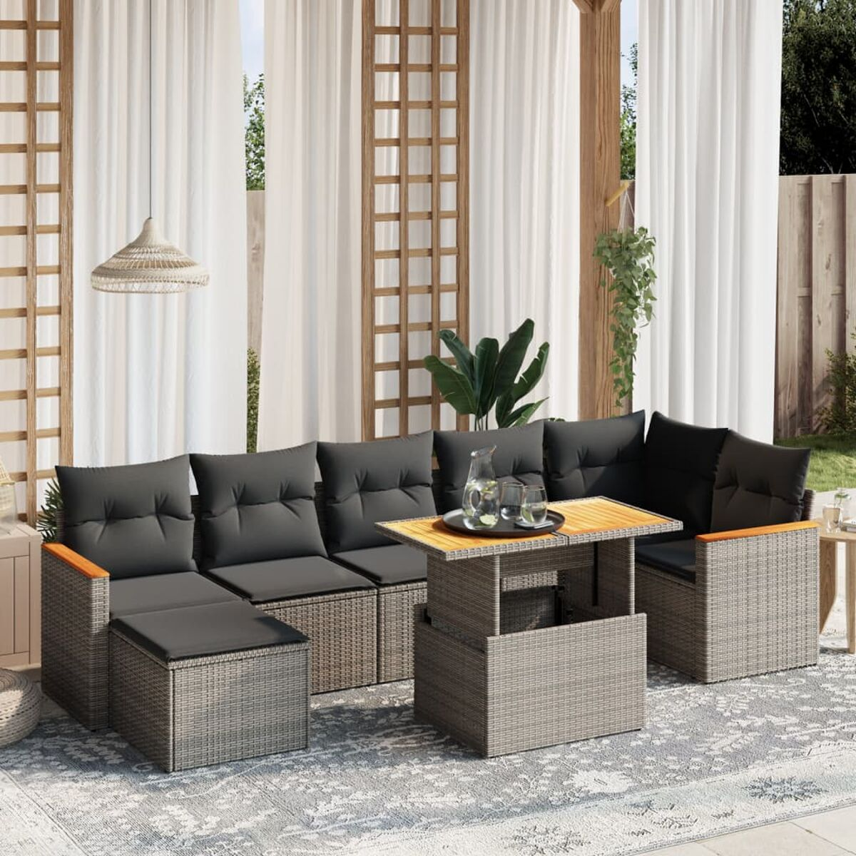 Ein Terrassen-Set: graues Rattan-Sofa, Tisch und Kissen unter einem Baldachin.