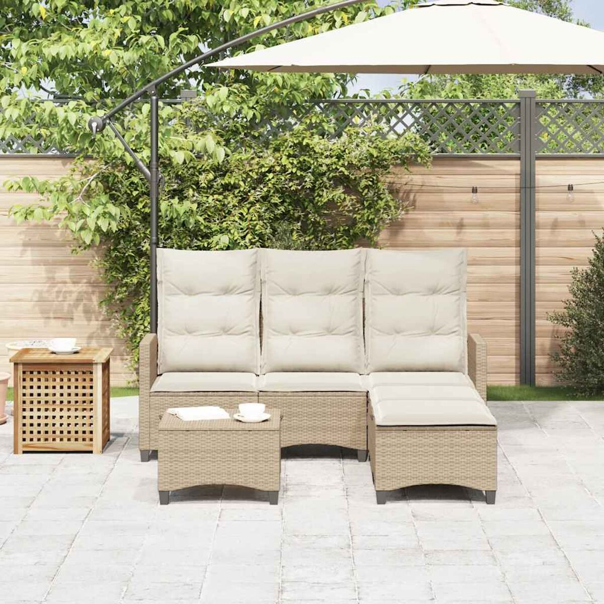 Set di sedute da esterno con divano, pouf e tavolo. Cuscini beige su mobili in vimini. Ombrellone sullo sfondo.