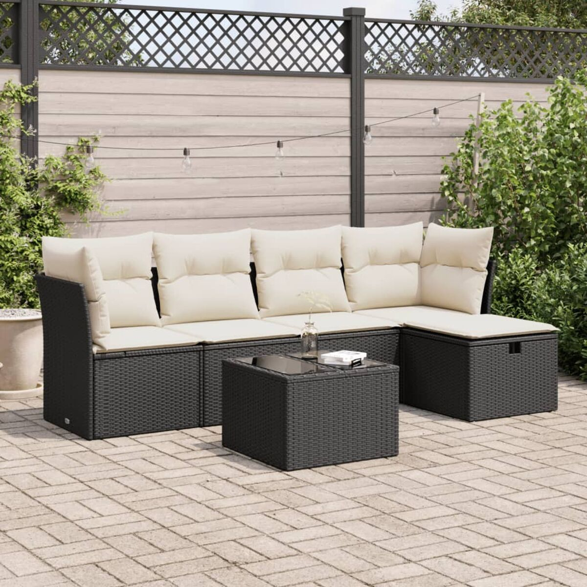 Schwarzes Ecksofa mit cremefarbenen Kissen und Tisch. Patio-Setting.