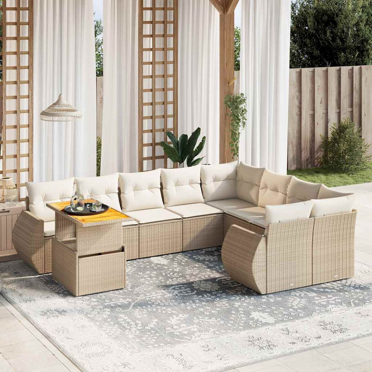 Set di mobili da esterno in vimini con cuscini beige, un tavolo e un tappeto fantasia. Luce diurna.