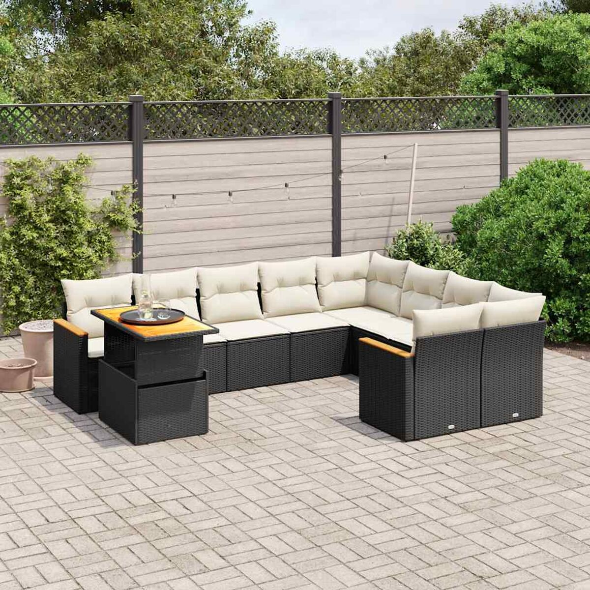 Schwarzes Rattan-Ecksofa mit cremefarbenen Kissen. Es gibt einen kleinen Tisch. Der Hintergrund ist eine Terrasse.