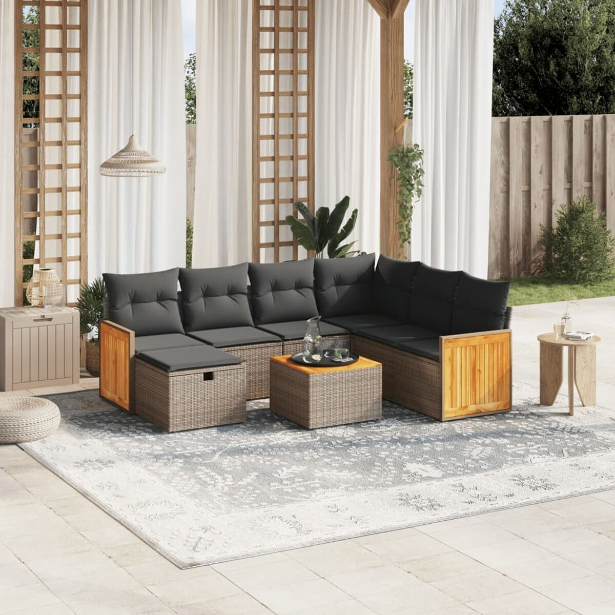 Garnitur im Freien auf der Terrasse. Sofa, Tisch und Ottomanen. Beige Kissen, graues Korbgeflecht.
