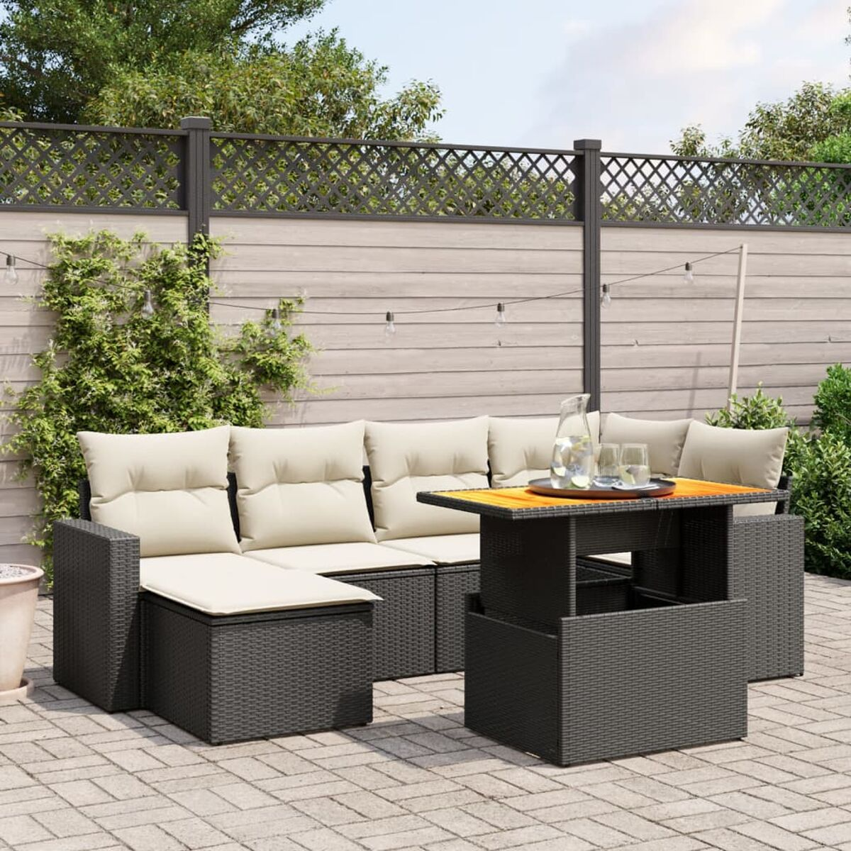 Graues Outdoor-Korbsessel-Set mit cremefarbenen Kissen und einem Couchtisch. Umzäunter Hintergrund.